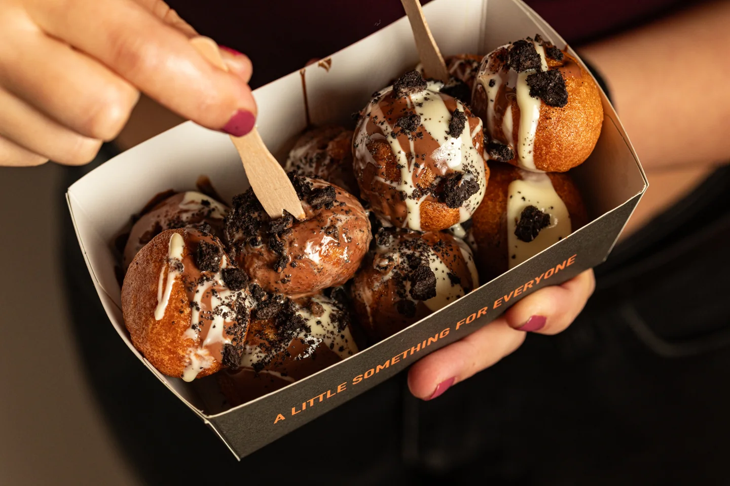 Sharing freshly topped Lookumades Loukoumades with chocolate sauce and cookie crumbs