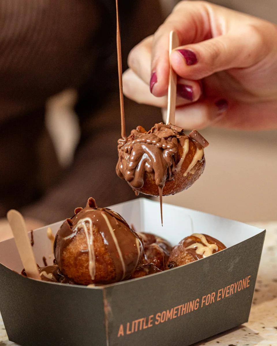 Chocolate sauce drizzling over a golden doughnut lifted from a Lookumades box
