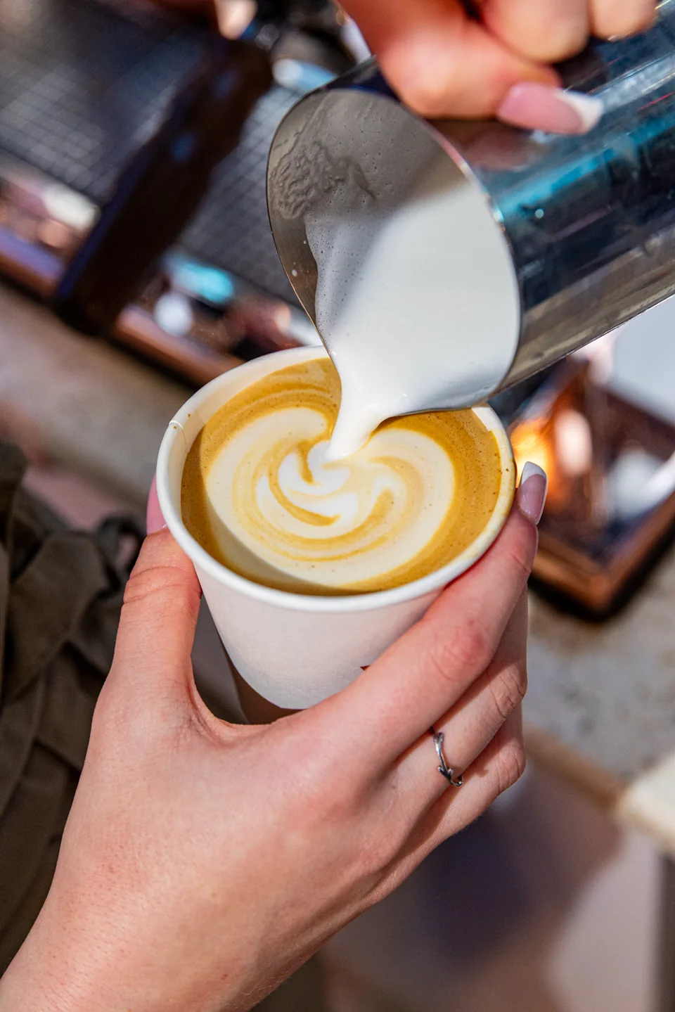 Barista pouring latte art into a Lookumades flat white