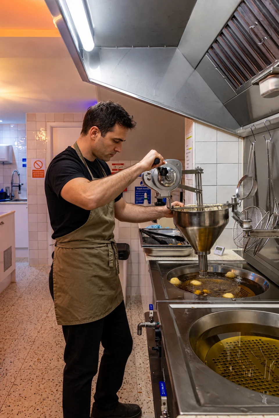 A cook preparing Loukoumades in the Lookumades kitchen; AI-edited person
