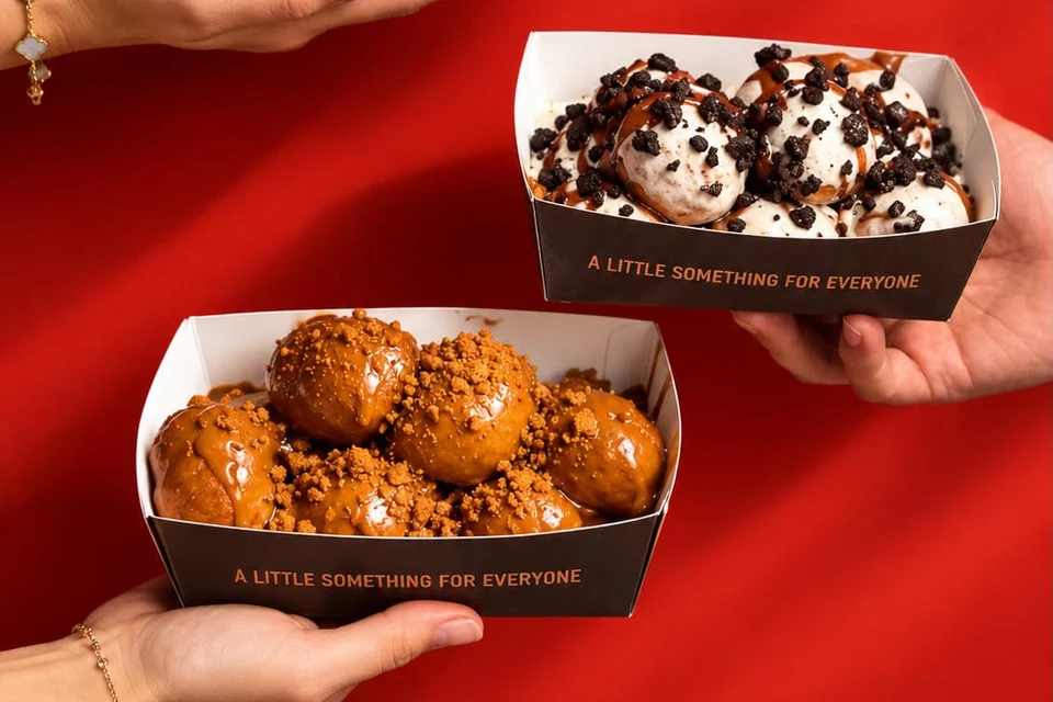 Oreo and Biscoff loukoumades in Lookumades boxes against a red wall